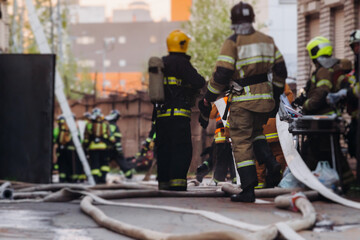 Group of fire men in uniform during fire fighting operation in the city streets, firefighters with...