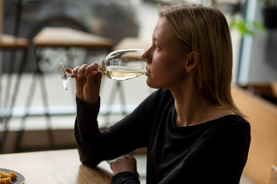 White blonde woman drinks wine