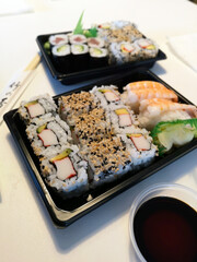 A delicious sushi bento box features fresh rolls, nigiri, and dipping soy sauce, beautifully arranged for a delightful dining experience.