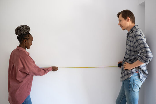 Diverse couple measuring wall
