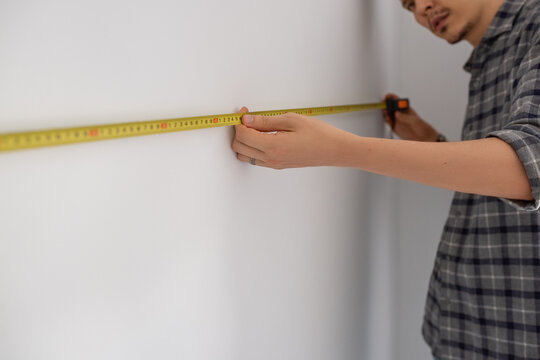 Focused man measuring wall