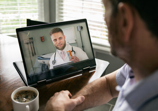 Distancing: Man Visits With Doctor Via Telemedicine On Laptop