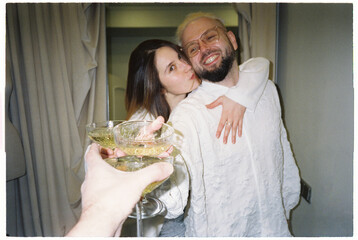 Joyful newlywed couple raising champagne glasses with groom best man