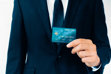 Portrait of businessman holding a credit card showing front view to the camera in close up view. Online shopping business and cashless payment concept. uds