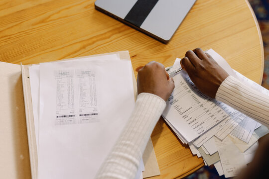 Cropped black young waitress checking payments and bills at table