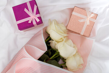 Postcard. White roses and gifts on a white, fabric background.