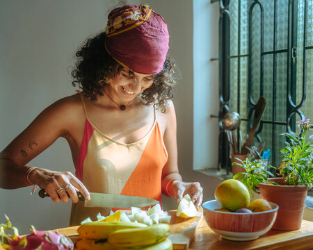Woman Preparing Fresh Fruit in a Bright, Sunlit Kitchen