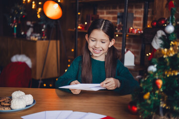 Photo of charming little girl write letter envelope dressed green christmas garment tradition atmosphere decor house indoors room