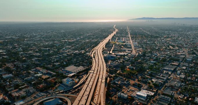 Several multi-lane highways go along together by the city scenery. Los Angeles panorama with busy roads. Aerial perspective.
