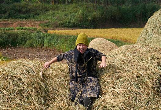 Asian lady happily playing on the straw bale