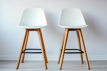 Two modern white bar stools with wooden legs arranged.