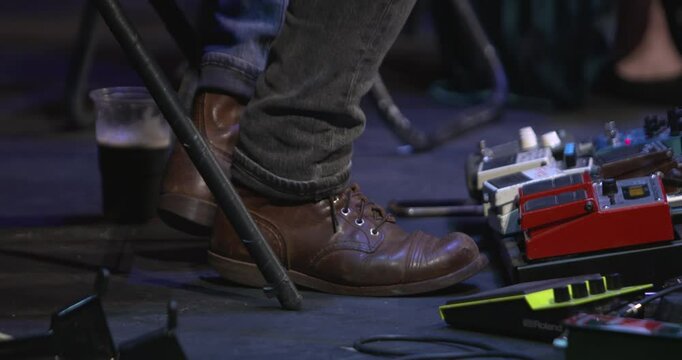 Musician taps his foot in time to music live stage performance guitar effects pedals