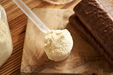 A scoop of whey protein powder on a table with homemade protein chocolate bars