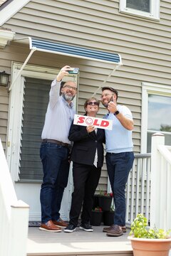 Couple Celebrating New Home with Selfie and Sold Sign