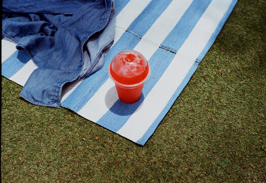 Freshly cold watermelon juice and strewn jeans jacket on blue mat