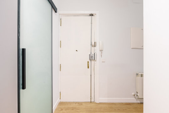 A white, minimalist apartment entryway with a closed front door