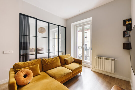 A modern living room with a mustard yellow sofa and wooden flooring