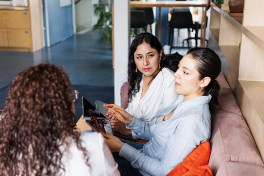 Women chatting on a couch in a coworking space.