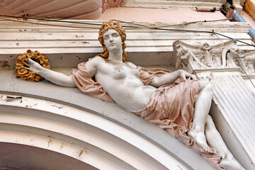 A weathered architectural sculpture of a female figure on a historic building facade in Sibiu,...