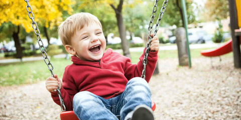Portrait of a child swinging on a swing on a sunny day at a playground and laughing