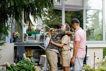 Couple hugging and saying goodbye friends after resting on terrace