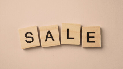 Obraz premium Word of Sale. Text written by wood toy or wood cubes on white paper background with texture. Top view of wooden english alphabet arranging to words. Close up of photo letter design wood toys.