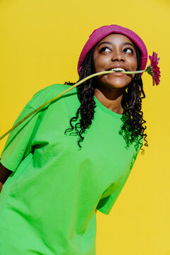 African woman holding pink flower in mouth