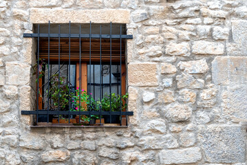 Window of stone built home with iron grates and plants on the sill - common in Spanish pueblos