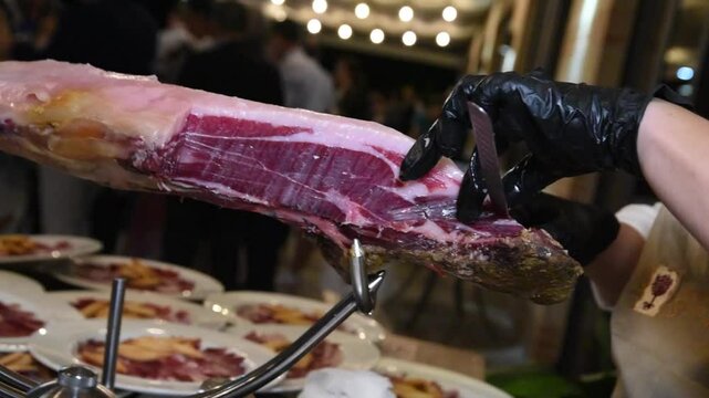 Chef cutting Spanish serrano ham - Serving serrano ham preparing food in a kitchen - Gourmet Spanish tapas plate with delicious serrano ham