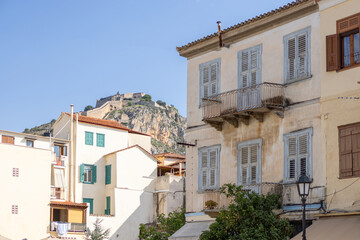 Stroll through Nafplio's picturesque streets adorned with traditional architecture. The ancient fortress looms majestically above, reflecting history beneath the bright blue sky.