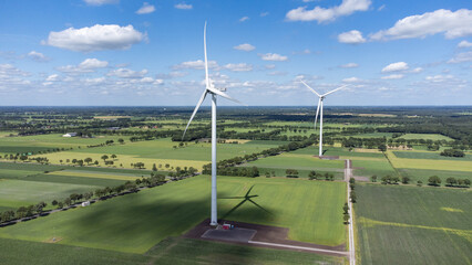 Landscape photo of two wind turbines in meadow farming field. Green renewable energy, global warming, climate change, sustainability, farm land concept. 
