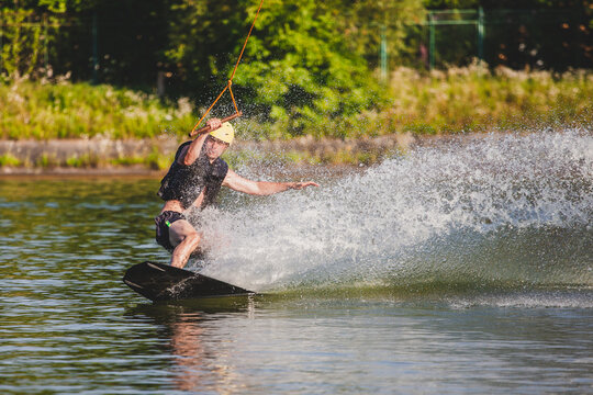 Man rides on wakeboard on lake.