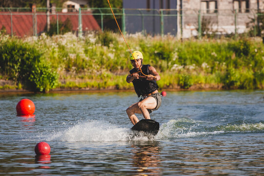 Man rides on wakeboard on lake.