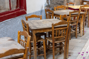 In the heart of Nafplio, Greece, rustic wooden tables sit quietly under the shade of lush leaves, creating a perfect setting for relaxed meals and warm conversations.