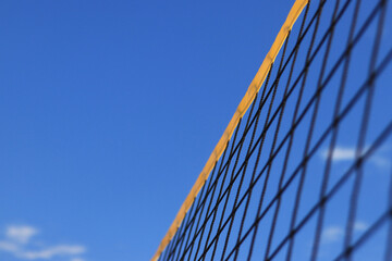Beach volleyball net close-up. Fragment of a volleyball net on the beach against the blue sky. Sport, beach volleyball. Active recreation concept. Background. Detail of the yellow net. Sports ground