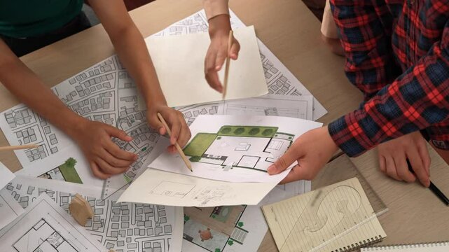 Smart architect and safety engineer discussion about building blueprint on table with architectural document, measurement tools and wooden block scatter around at modern office. Closeup. Delineation.