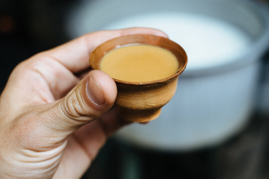A hand holding a traditional clay cup filled with chai in India