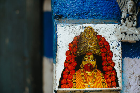 Colorful mural of a deity adorned with flowers in a vibrant alley