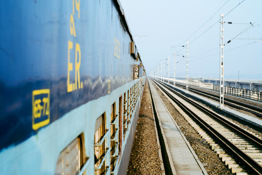 Train travels along tracks in a rural area during daylight
