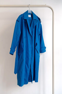 Blue Coat Hanging On A Hanger Against A White Background