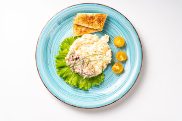 Scrambled eggs with mushrooms and crispy toast garnished with lettuce and yellow cherry tomatoes, on a turquoise plate, on a white table. Delicious and healthy breakfast. Copyspace