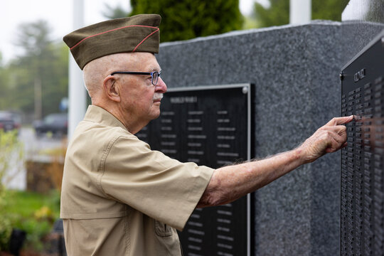 Senior Citizen military man at war memorial touch name