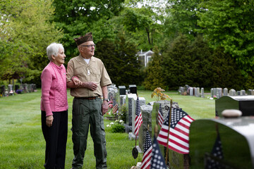 Senior military Veteran wife salutes at veteran cemetery landscape