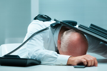 Complete breakdown, businessman hides under desk, overwhelmed