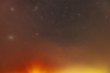 A peaceful night sky filled with faint stars and a soft red aurora glow near the horizon. The...