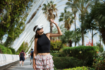 A woman wearing a VR headset is fully immersed in and enjoying an exquisite tropical garden