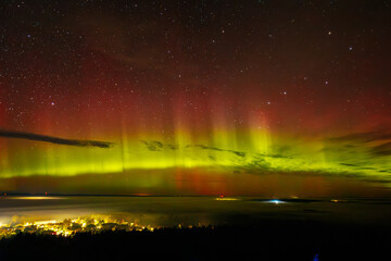 A vivid aurora borealis with striking red and green hues lights up the starry night sky above a...