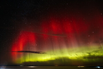 A stunning display of red and green auroras lighting up the night sky, with stars sparkling in the background. The vibrant celestial event creates a mesmerizing, ethereal atmosphere.