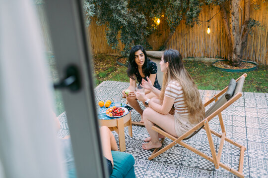 Best female friends having a backyard dinner party in summer, talking 