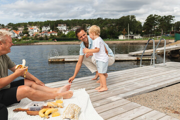 Dad and Playful Kid Observing Fish from Jetty on summer picnic